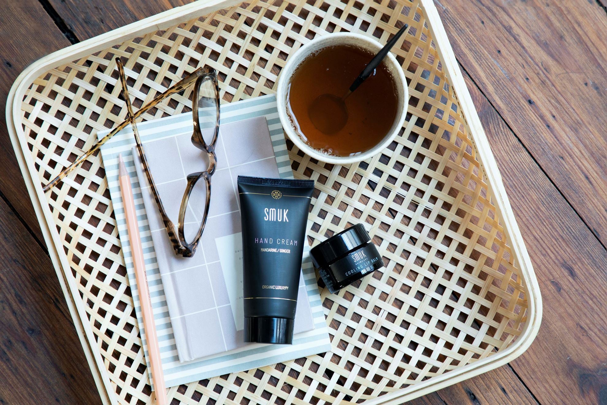 Bakke med kop te, briller og SMUK skincare håndcreme og lip balm