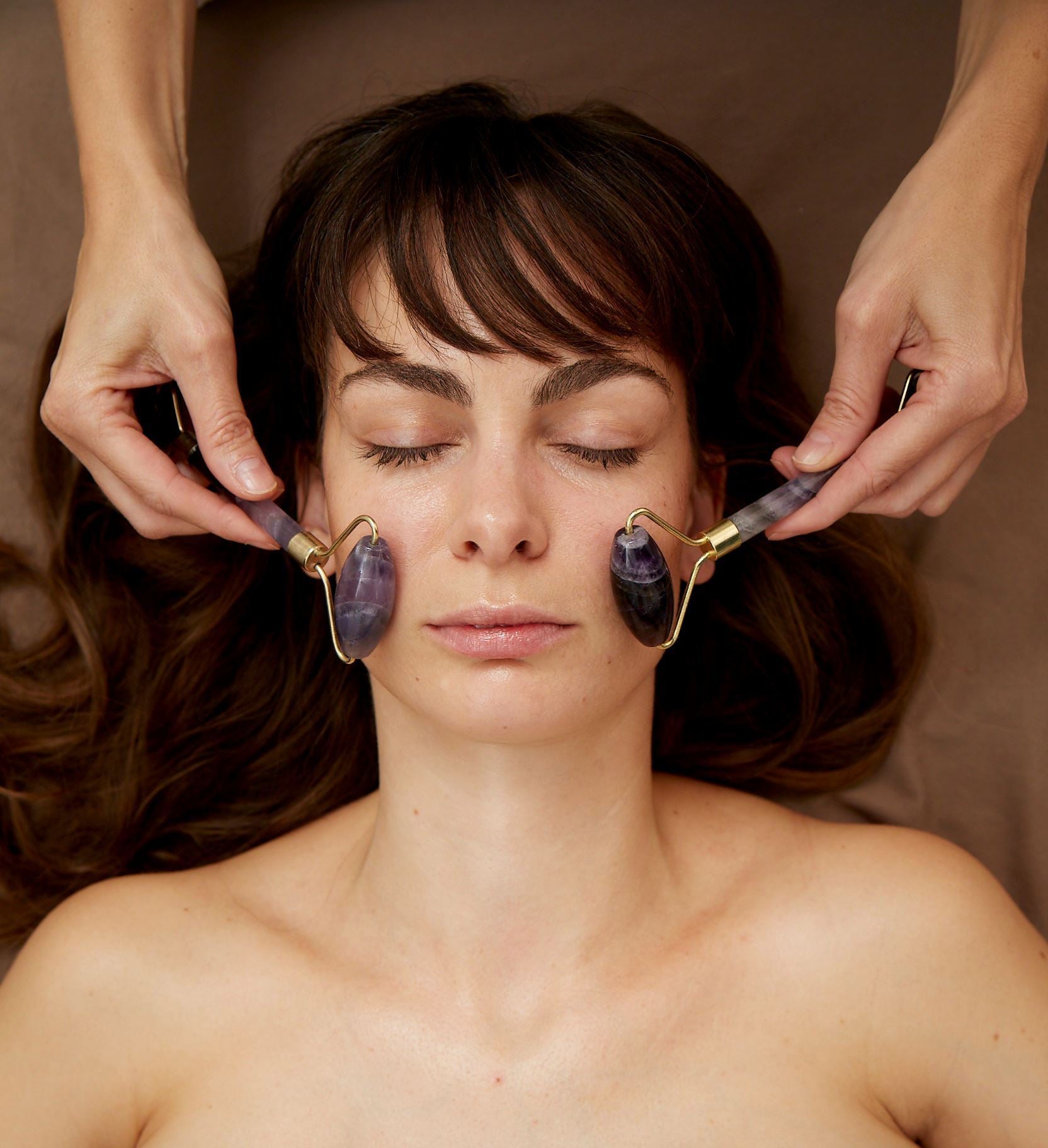 Kvinde i skønhedsklinik får ansigtsmassage med beauty tool derma rolls