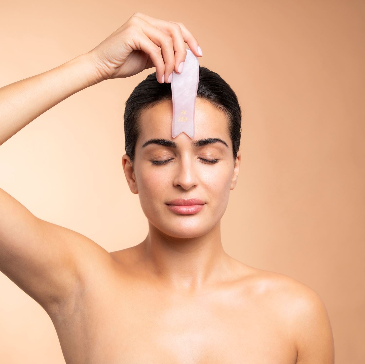 Kvinde bruger rosakvarts gua sha beauty tool