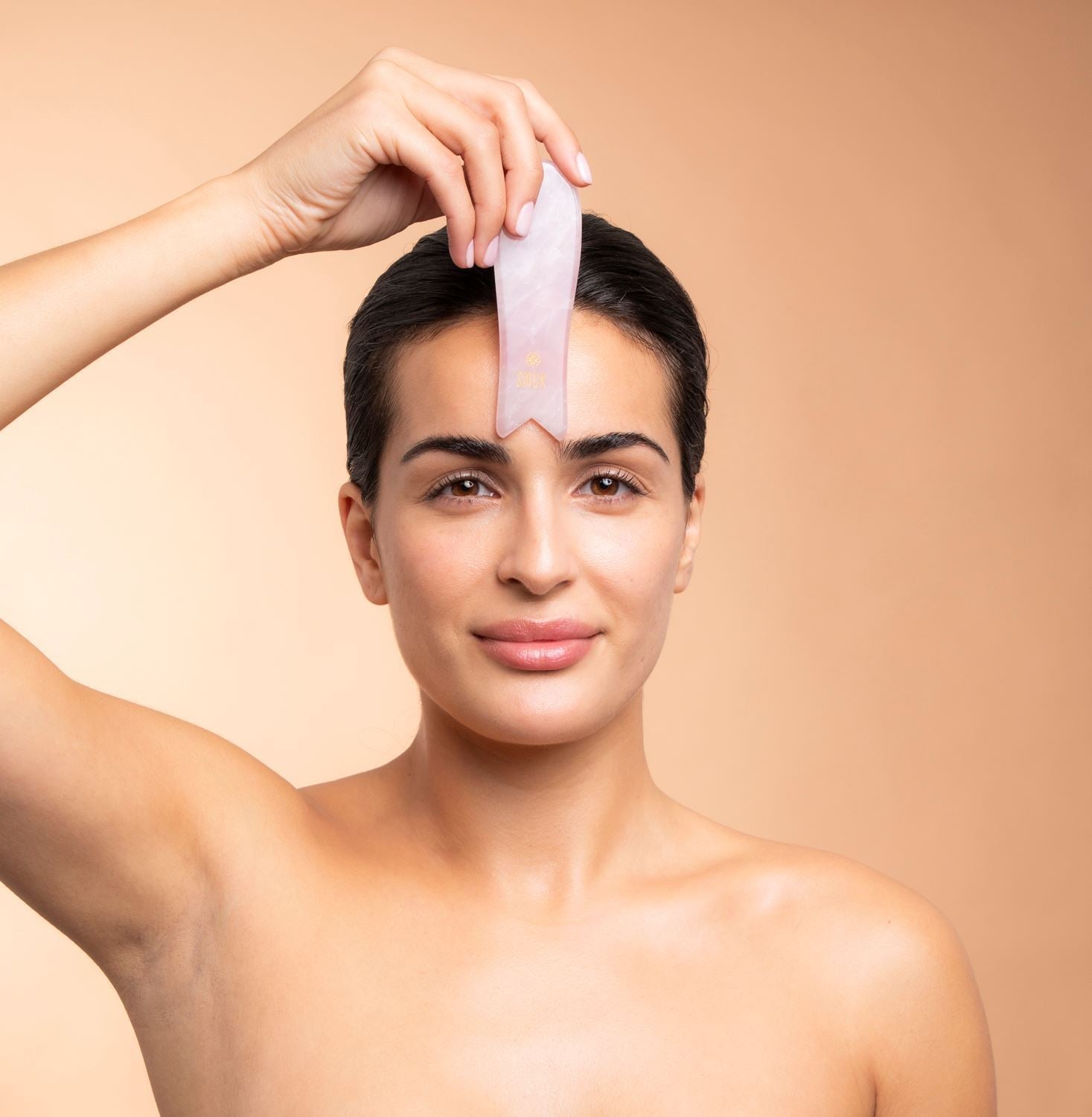 Kvinde bruger rosakvarts gua sha beauty tool