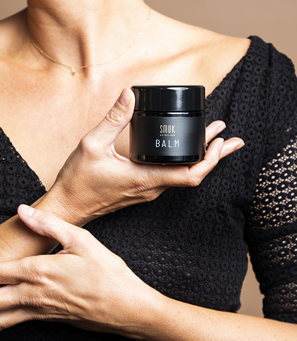 Kvinde holder sort dåse med SMUK skincare økologisk balm