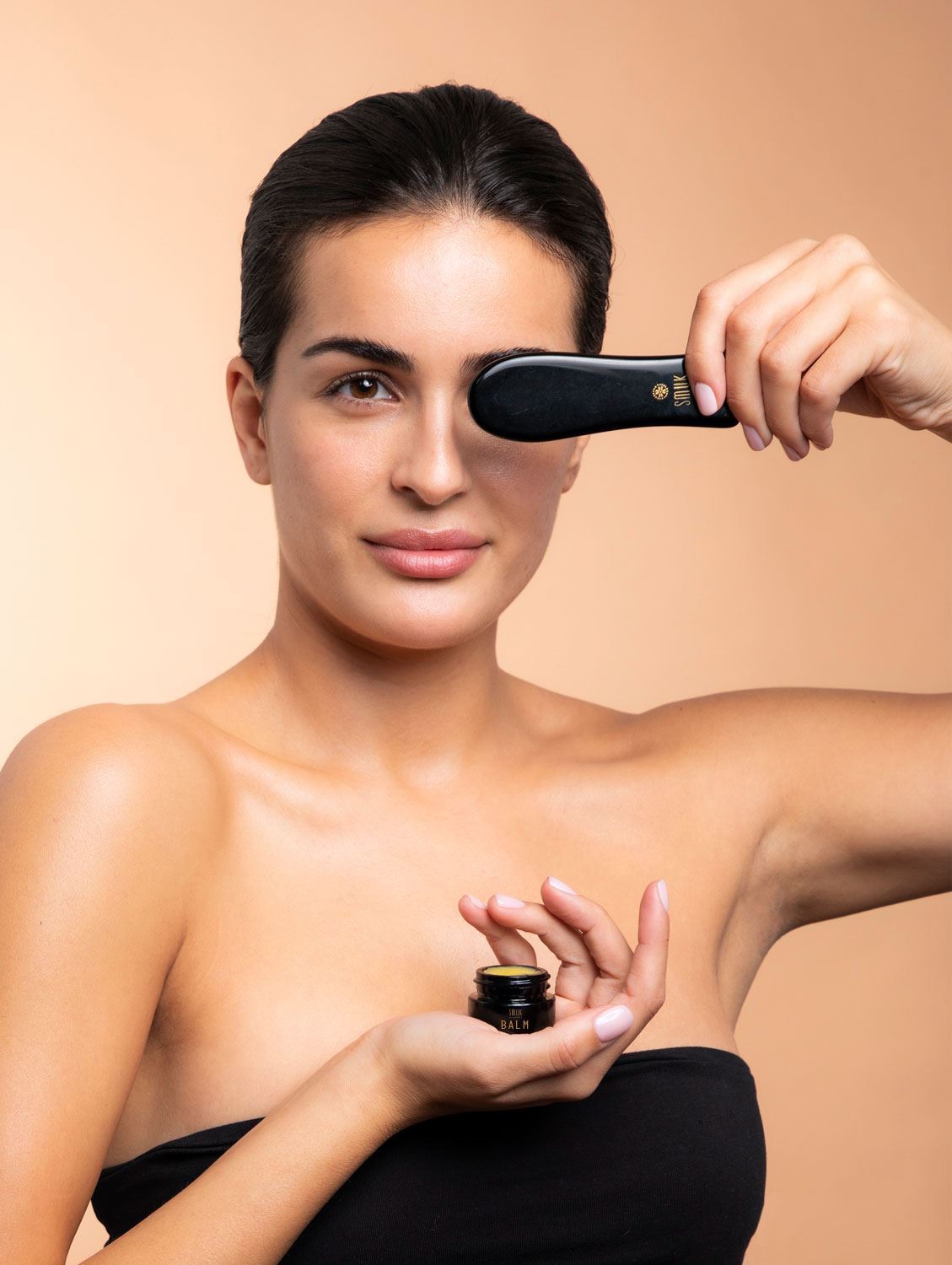 Kvinde med SMUK skincare økologisk balm i sort dåse og gua sha beauty tool