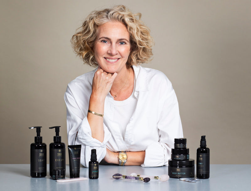 Heidi ved bord med SMUK skincare produkter til ansigt og krop i studieopsætning