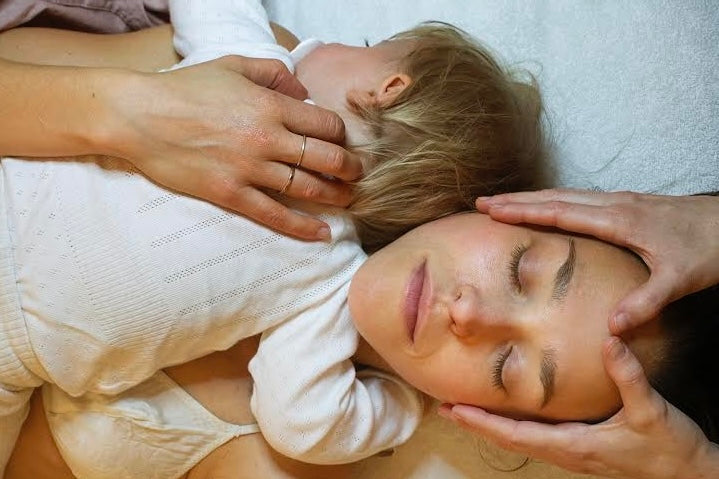 Kvinde, der holder en baby på sit bryst, får en ansigtsmassage